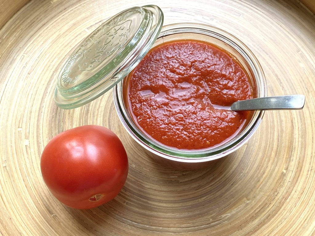 Een schaaltje met hot ketchup en een tomaat ernaast