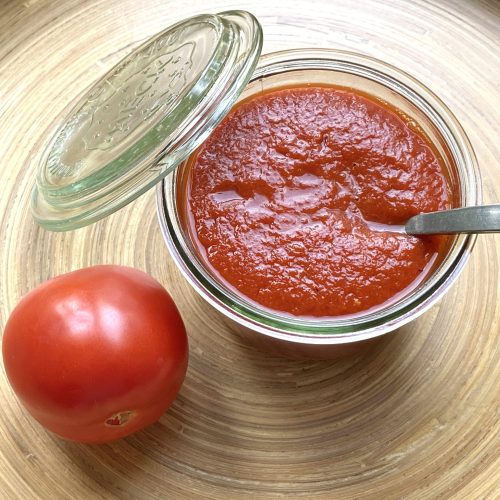 Een schaaltje met hot ketchup en een tomaat ernaast