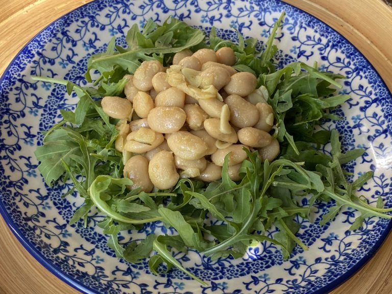 Limabonen in rozemarijn-knoflookboter op een bedje van rucola