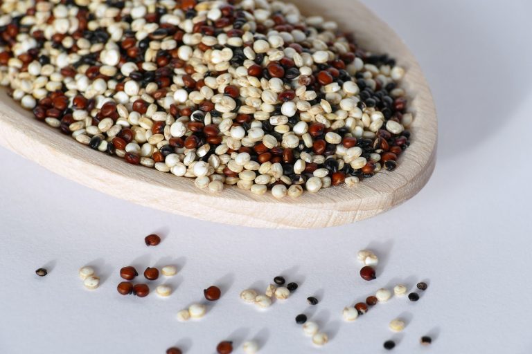 Lepel gevuld met ongekookte quinoa in drie kleuren