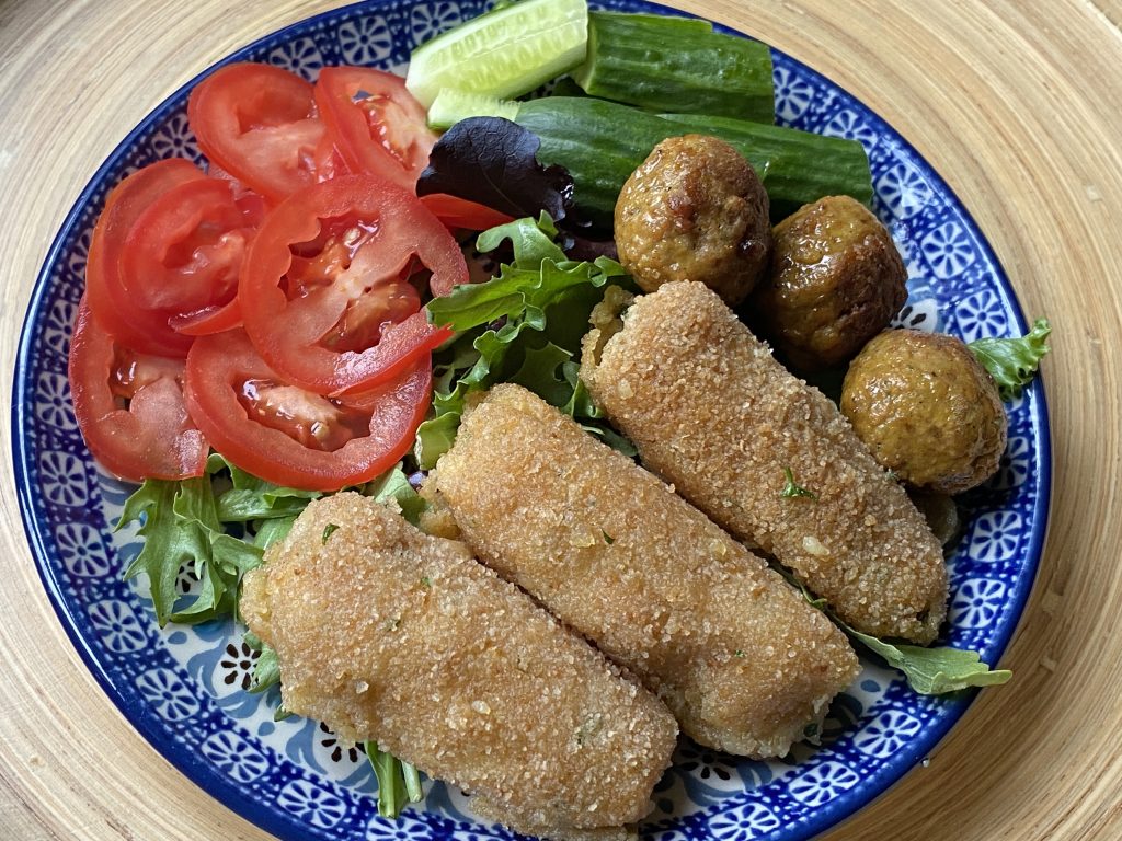 Bord met salade, aardappelkroketjes en vegan balletjes