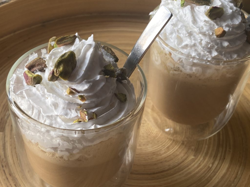 Twee glazen met pistache frappucino, slagroom en gehakte pistachenootjes