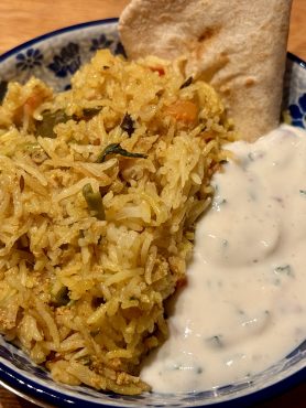Een schaaltje met biryani, raita en roti