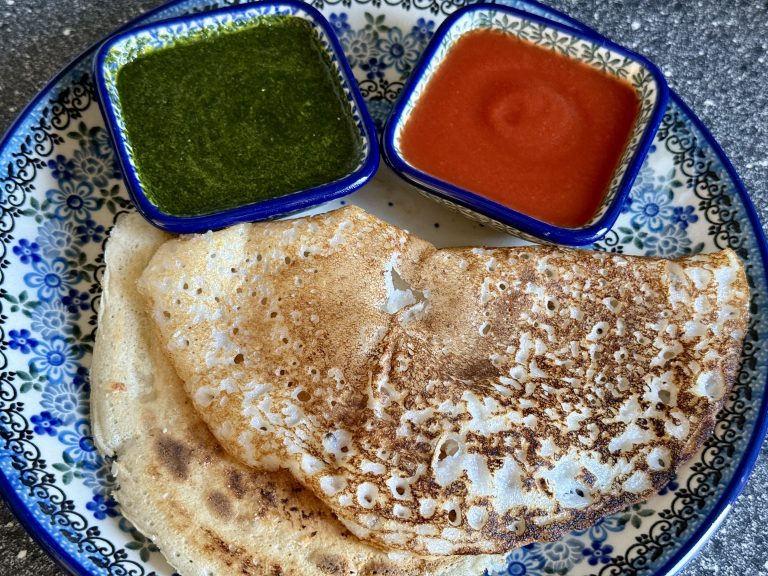 Een bord met twee dosa’s, een schaaltje groene chutney en een schaaltje tomatensaus