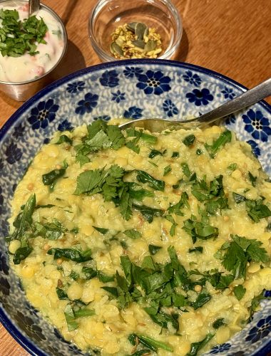 Een schaal met khichdi met spinazie en specerijen, een bakje ui-tomaatraita en een bakje met mukhwas