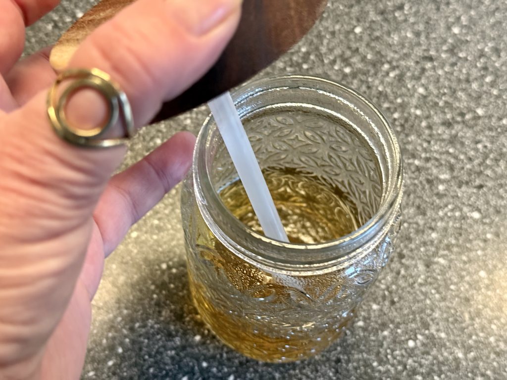 Een glas met deksel en rietje, daarin een heerlijk Indiaas ochtenddrankje: ajwain-pani