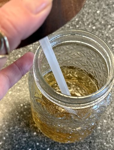Een glas met deksel en rietje, daarin een heerlijk Indiaas ochtenddrankje: ajwain-pani