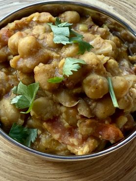Pindi chole in een roestvrij stalen bakje, koriander er bovenop