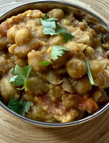 Pindi chole in een roestvrij stalen bakje, koriander er bovenop