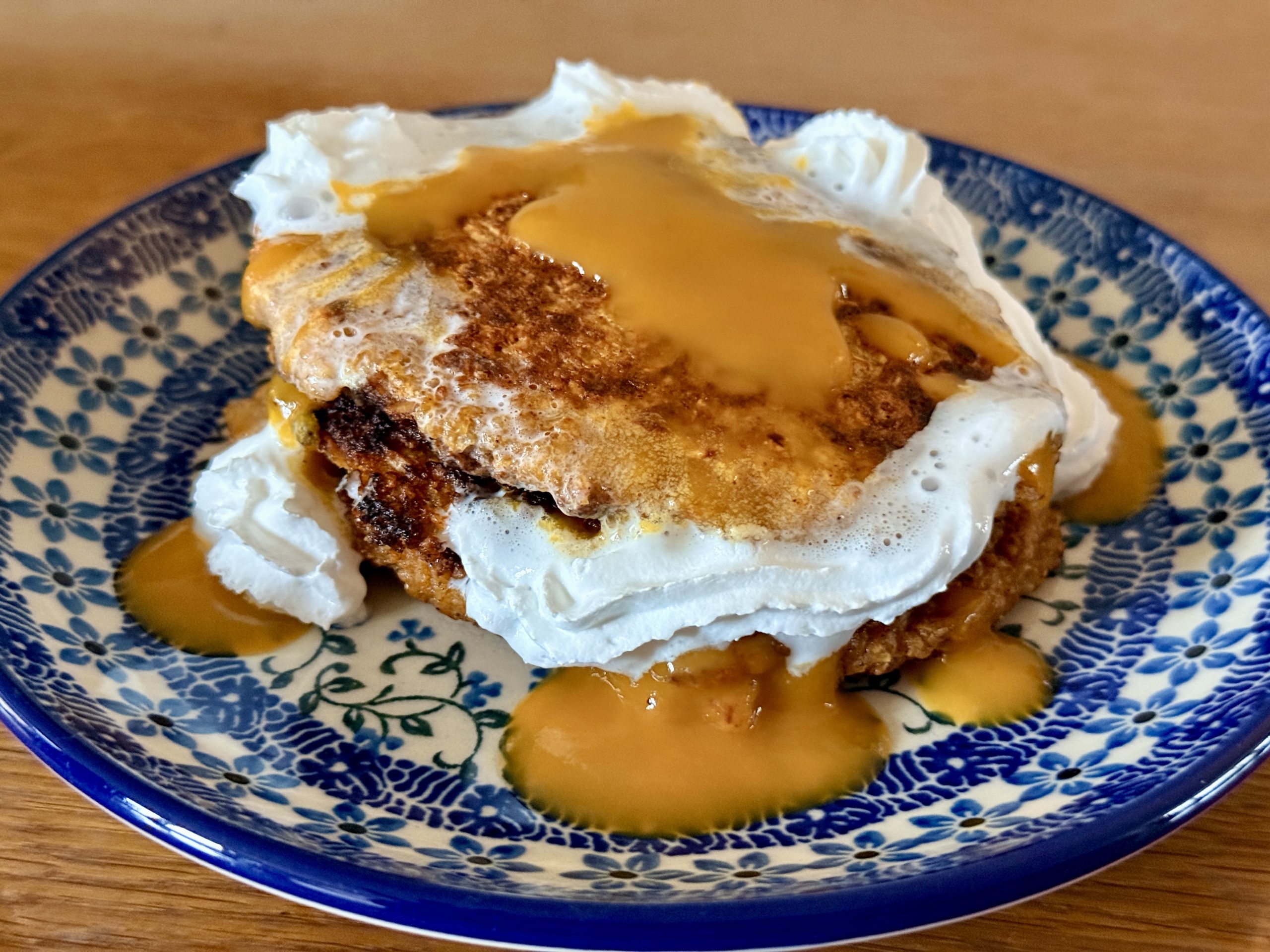 Pompoen-havermout pancakes met kaneel met mangopulp en slagroom op een Bunzlau bordje